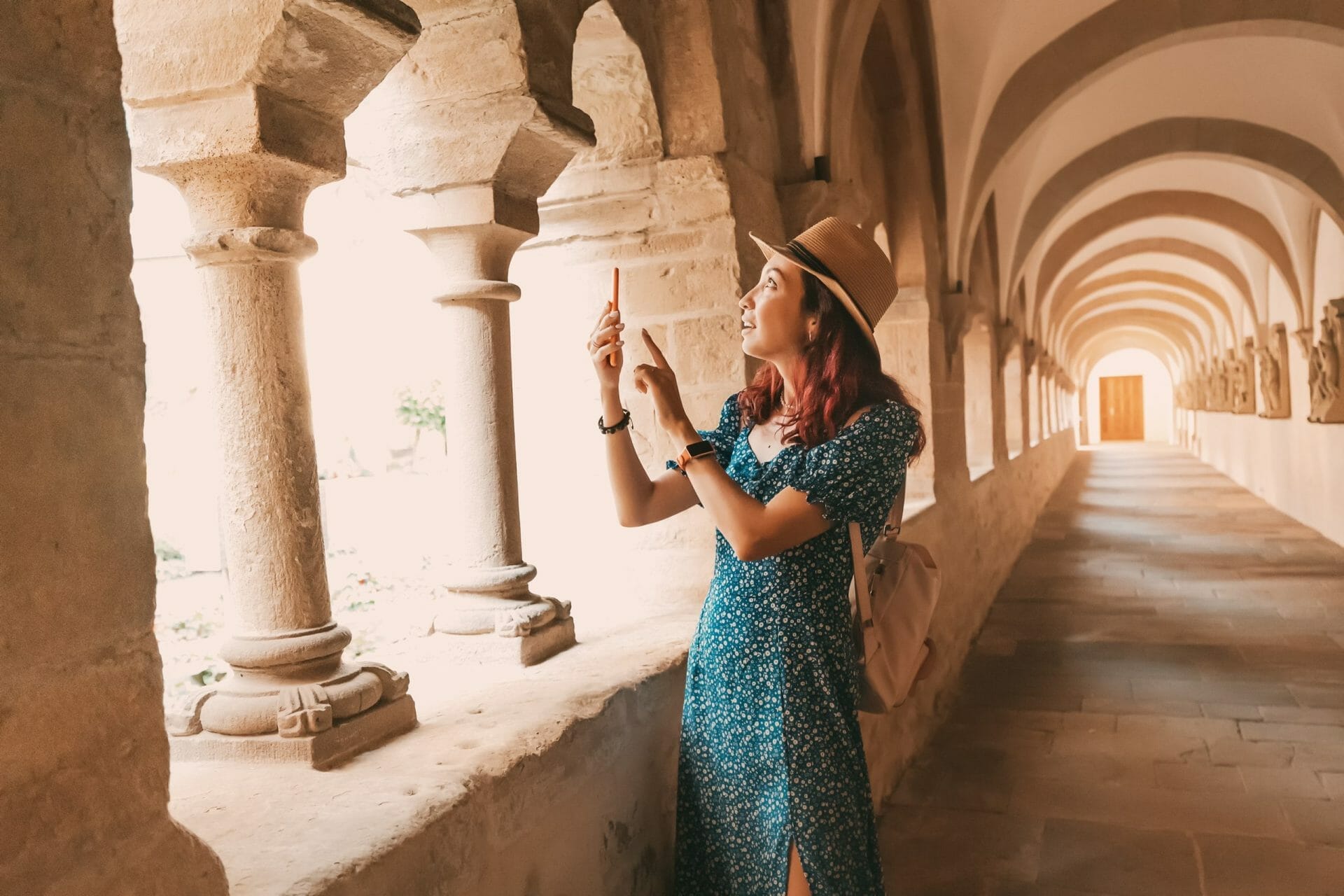 A Girl Traveler And Tourist Taking Mobile Photos In The Arch Of An Ancient Monastery Or The Courtyard Of The Cathedral