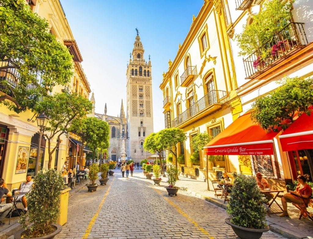 Café-lined street in Santa Cruz leading to the Giralda, Seville, Spain