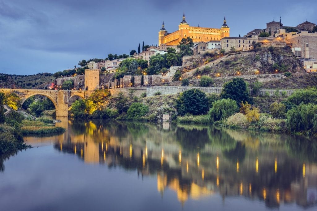 Alcázar and old town above the Tagus and the Alcántara bridge at dusk, Toledo, Spain