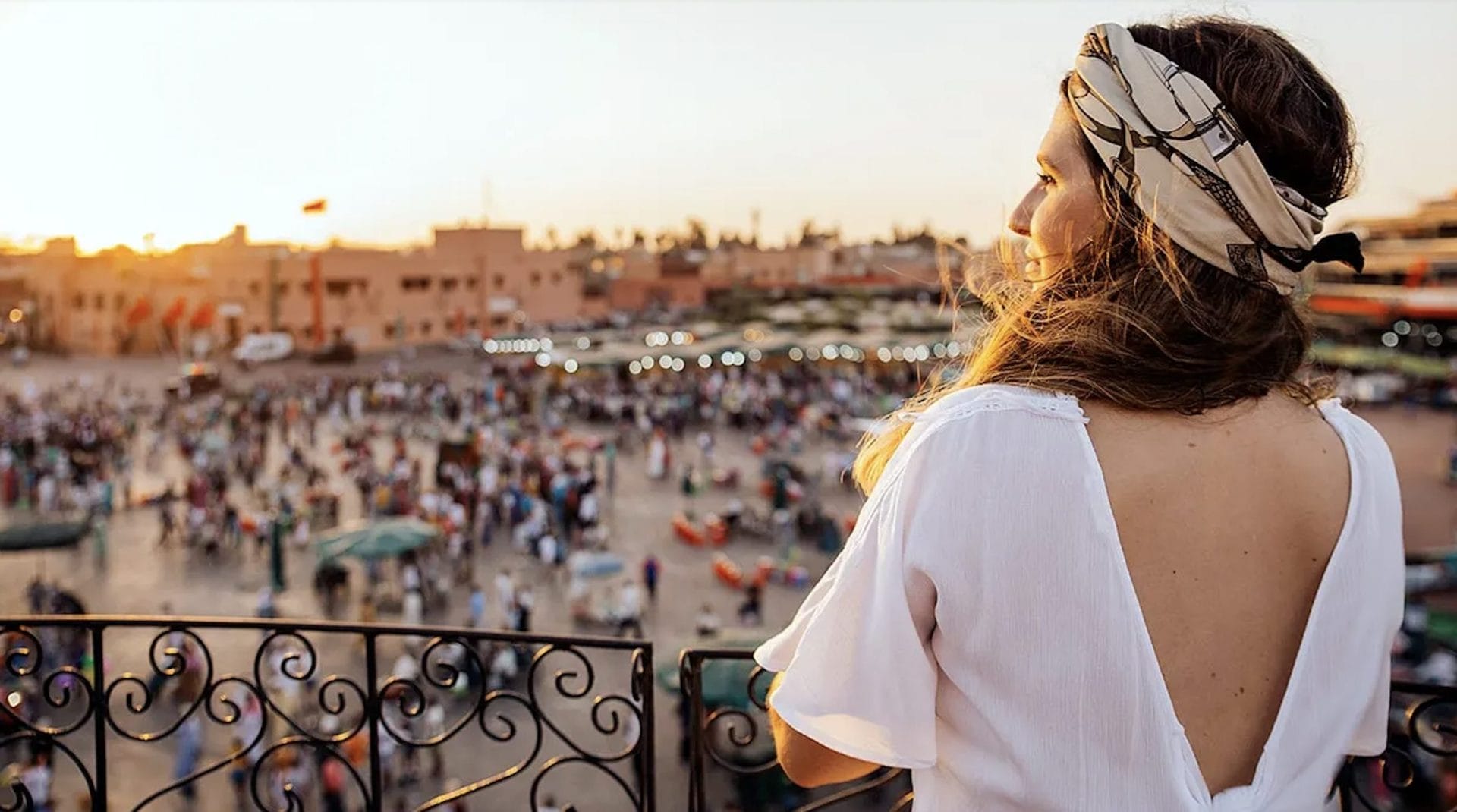 Woman overlooking Jemaa el-Fna from a rooftop terrace in Marrakech at dusk