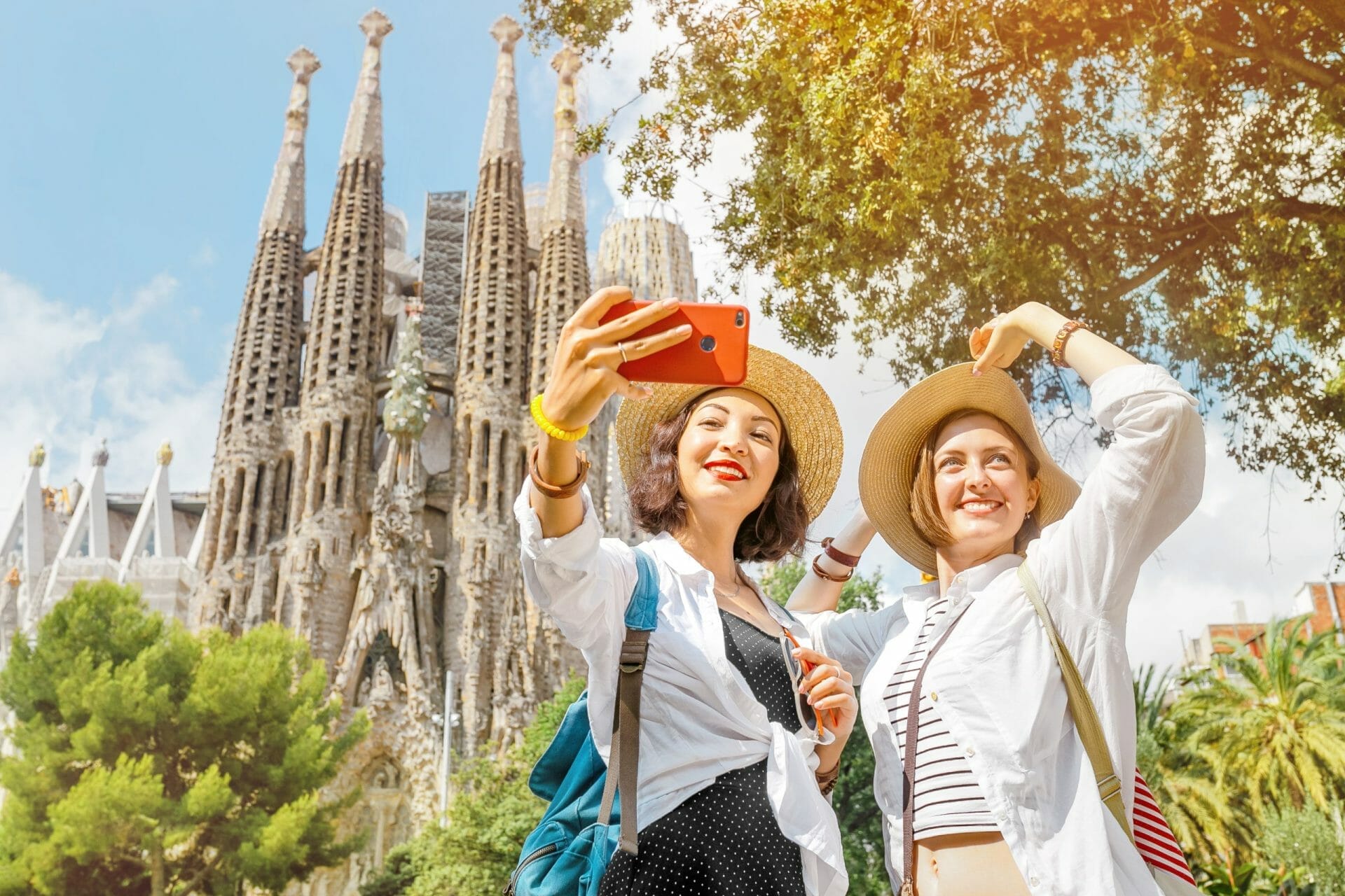 Barcelona, Spain Friends Making Selfie Photo On Her Smartphone In Front Of The Famous Sagrada Familia Catholic Cathedral. Travel In Barcelona Concept