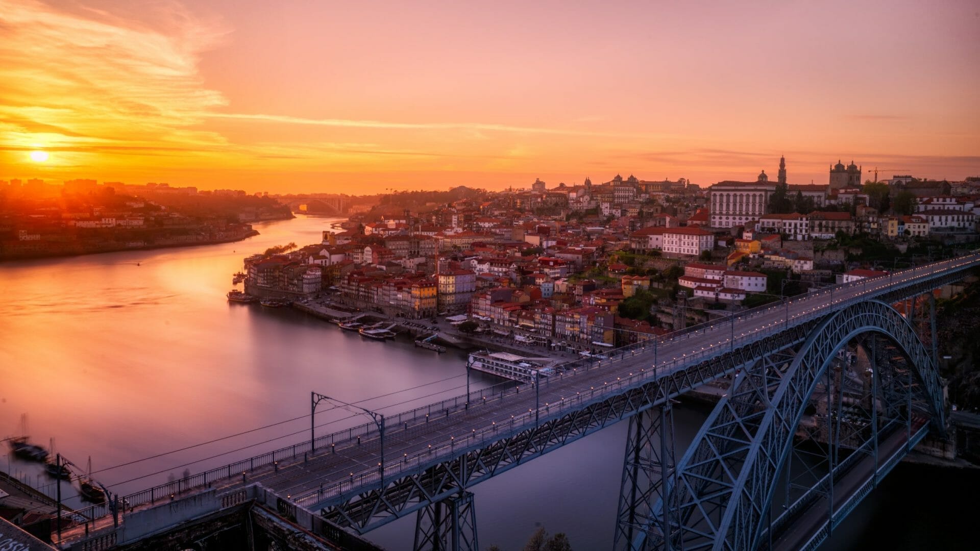 The Dom Luís I Bridge over the Douro River at sunset, with the historic center of Porto on the hillside, Portugal