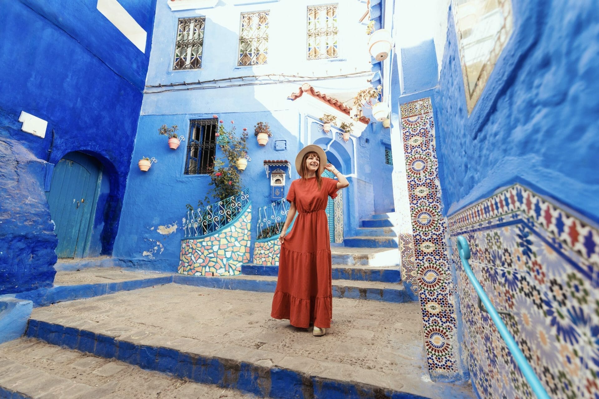 Young Woman With Red Dress Visiting The Blue City Chefchaouen, Marocco Happy Tourist Walking In Moroccan City Street Travel And Vacation Lifestyle Concept