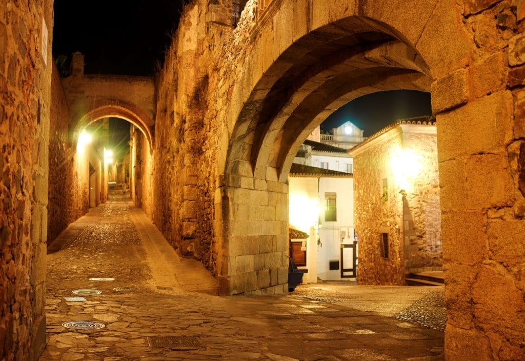 Arco de la Estrella gateway lit at night in the old town of Cáceres, Extremadura, Spain