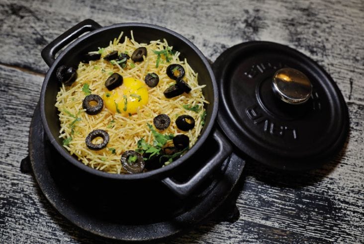 Bacalhau à Brás, shredded salt cod with straw potatoes, egg yolk and black olives, served in a cast iron pot, Portugal