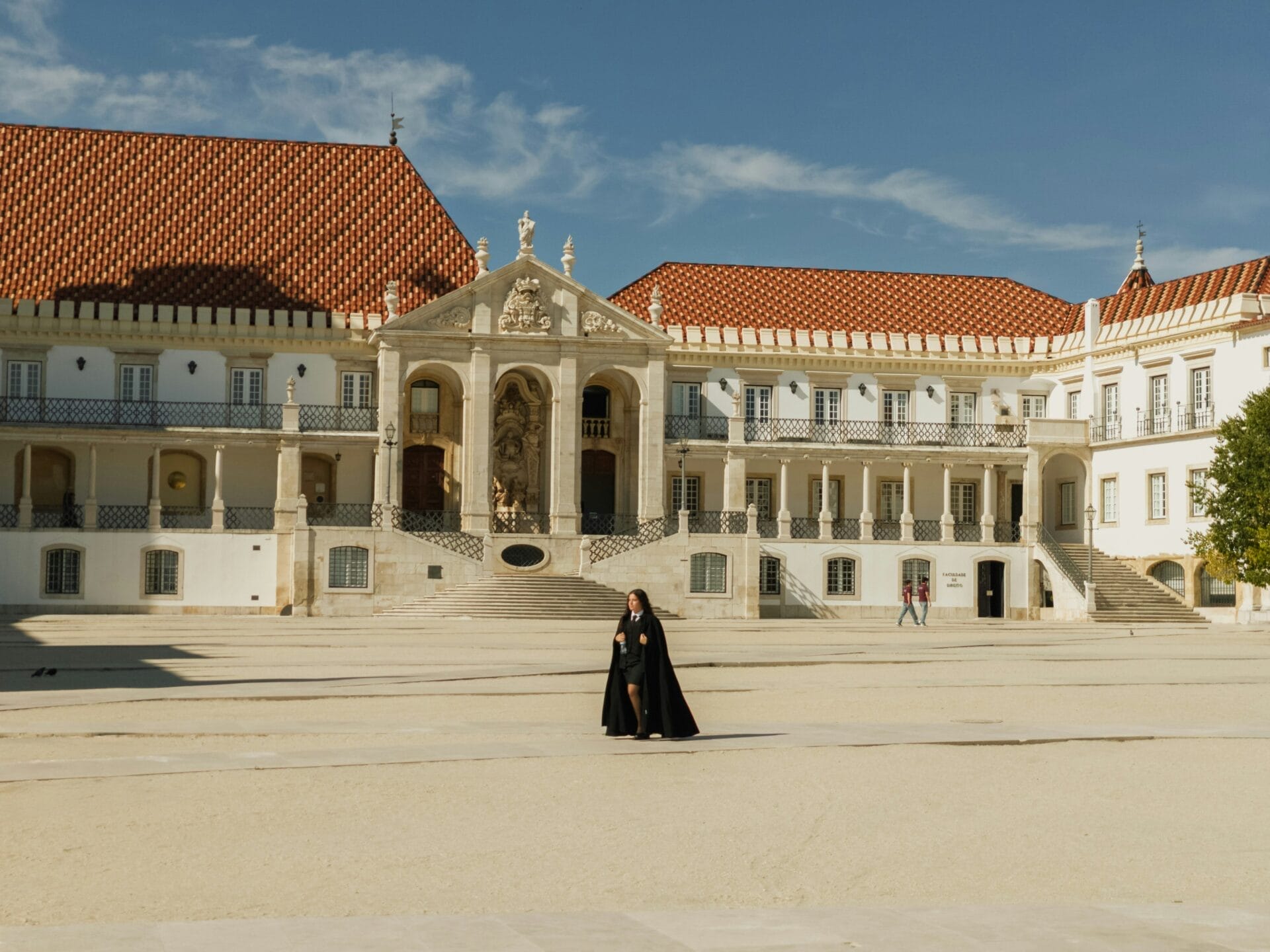 Student in a traditional black cape crossing the Pátio das Escolas, University of Coimbra, Portugal