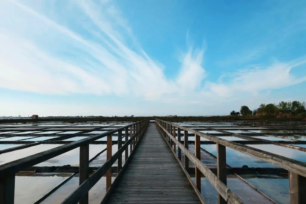 Wooden boardwalk stretching across the salt pans of Aveiro under a wide blue sky, Portugal