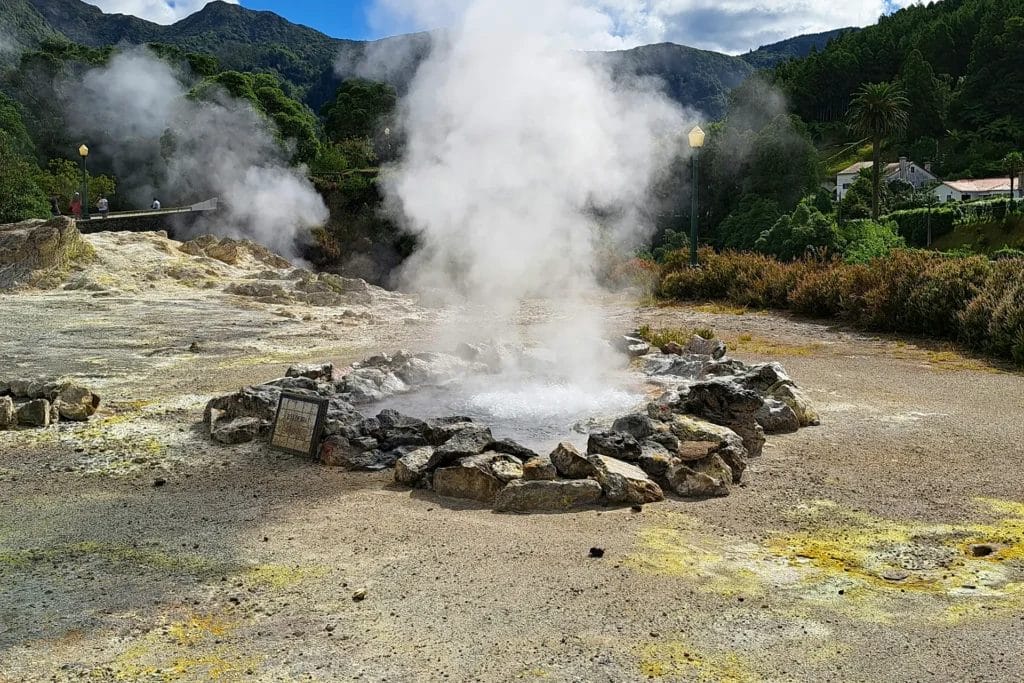 Steam rising from volcanic fumaroles ringed by stones at Furnas, São Miguel, Azores, Portugal