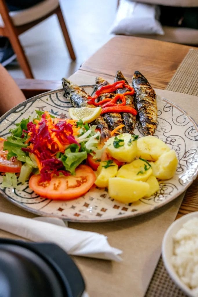 Plate of grilled fish with boiled potatoes and a fresh tomato and carrot salad at a Portuguese table