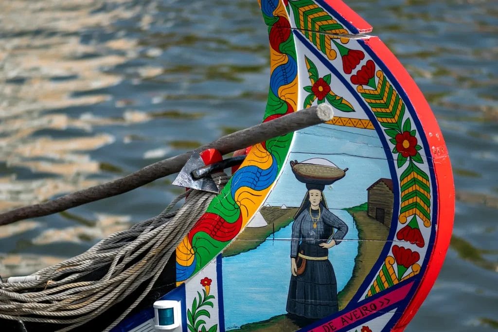 Hand-painted prow of a moliceiro boat with a folk scene in bright colours, on the canal in Aveiro, Portugal