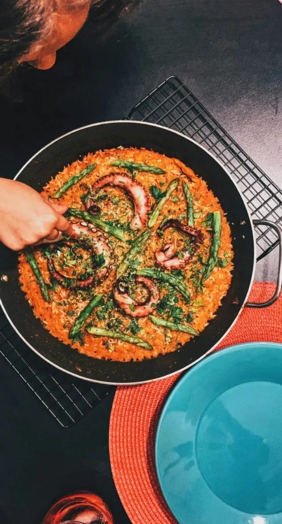 Pan of Portuguese octopus rice with tender octopus, green beans and tomato-rich rice, served at the table