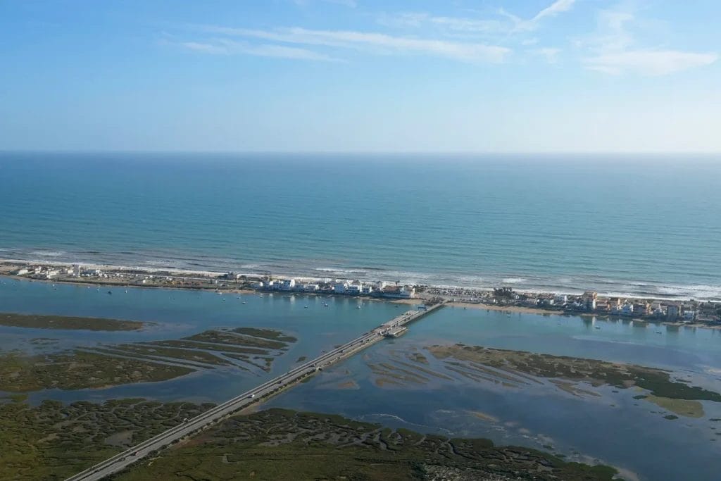 Aerial view of the Ria Formosa lagoon, its tidal channels and a bridge crossing to the barrier island beach, Algarve, Portugal