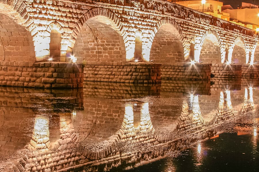 Arches of the Roman bridge over the Guadiana lit at night, Mérida, Spain